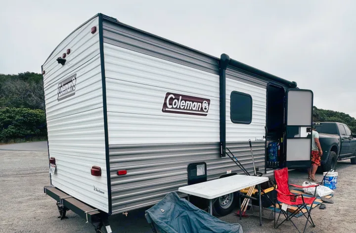 Relaxing by a Coleman/Dutchmen travel trailer, an RV rental with outdoor gear ready for a camping adventure.. Dutchmen Coleman Lantern LT 2023