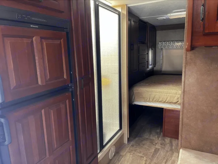 RV rental interior: Dometic fridge, glass shower, and bedroom with wood cabinets & TV for compact living.. Forest River Sunseeker 2016