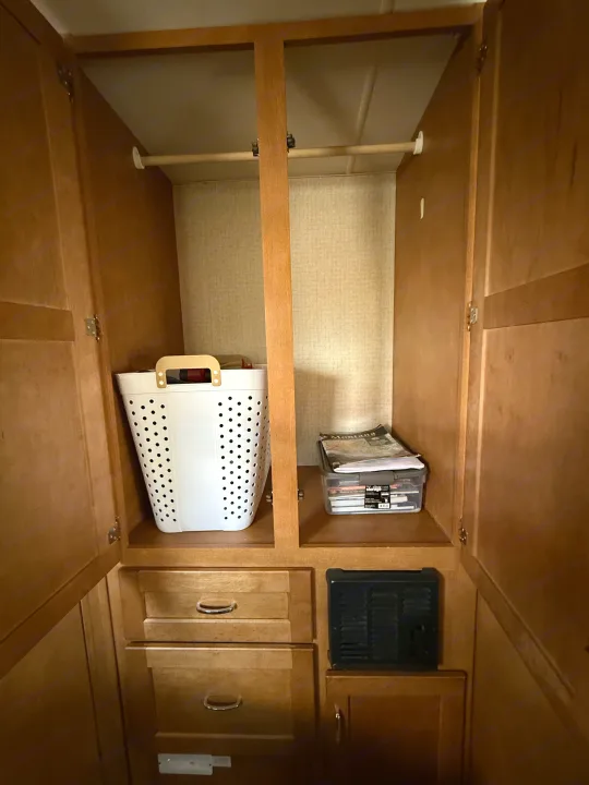 Inside an RV rental: a wood closet/cabinet with hanging rod, laundry hamper, clear storage bin, and drawers below.. Winnebago Minnie Winnie 2016