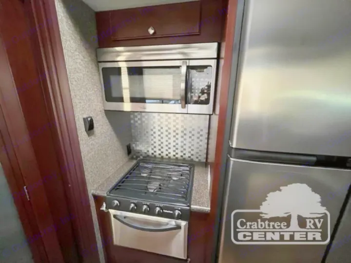 This RV rental features a modern compact kitchen with stainless microwave, gas stove/oven, and a large refrigerator.. Heartland Road Warrior 425 2016