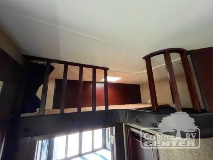 RV rental interior: elevated sleeping loft with wooden railings and a separate bunk area, maximizing space.. Heartland Road Warrior 425 2016