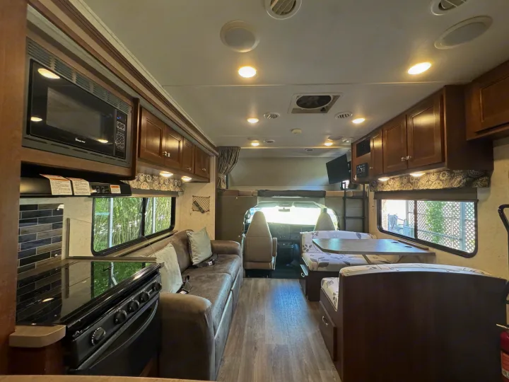 Spacious RV rental interior with a full kitchen, comfortable couch, dinette, and overhead bunk. Ideal for travel.. Forest River Sunseeker 2017