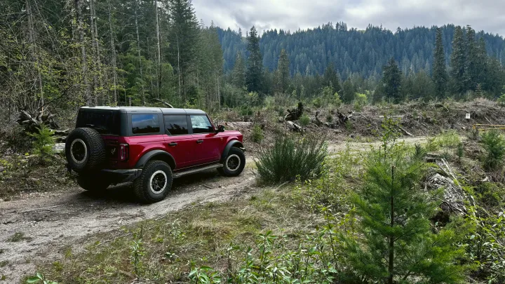 A red Ford Bronco on a rugged forest road. Explore wilderness areas inaccessible by typical RV rental vehicles.. Ford Bronco Badlands 2023