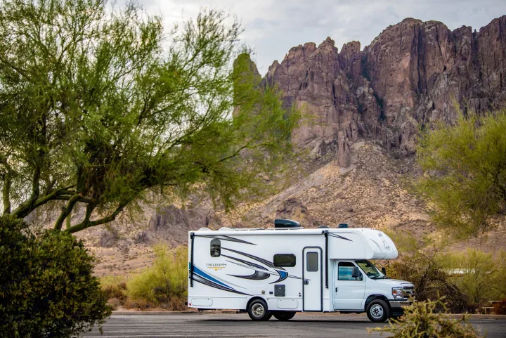White RV rental parked in a desert landscape with large, rugged mountains and a cloudy sky.. Nexus Other 2026