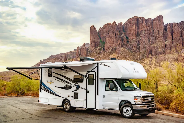 White RV rental with awning extended, parked before the majestic Superstition Mountains. Your desert adventure awaits!. Nexus Other 2026