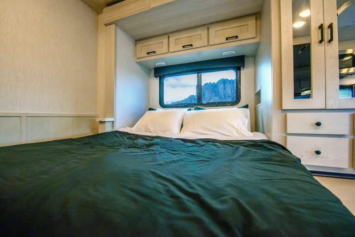 Serene RV rental bedroom, featuring a large bed, overhead cabinets, and a stunning mountain view from the window.. Nexus Other 2026