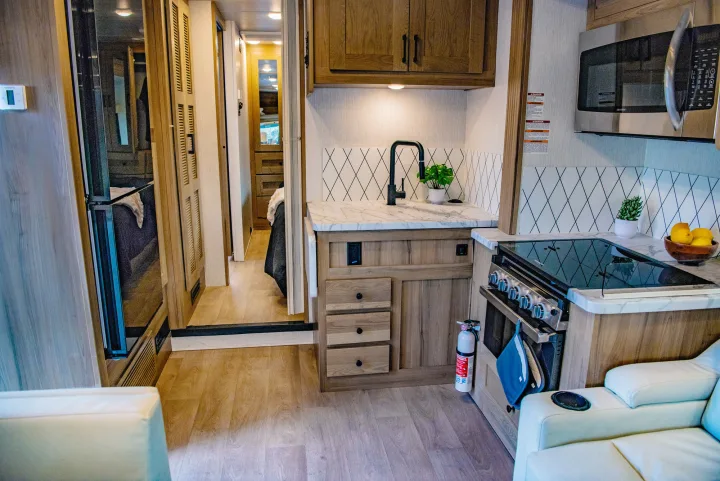 Modern RV rental interior featuring a spacious kitchen, living area, and a glimpse of the bedroom beyond.. Nexus 29T 2026