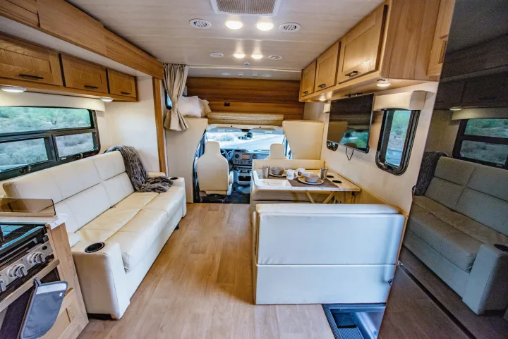 Bright, spacious RV rental interior: dinette, sofa, overhead bunk, and front cockpit view. Ready for your adventure.. Nexus 29T 2026