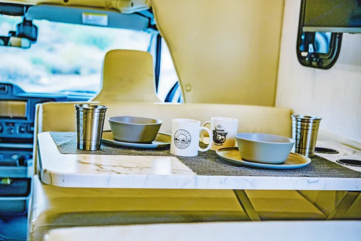 Your rv rental's dining table is set with plates, bowls, mugs, & cups for comfortable travel.. Nexus 29T 2026