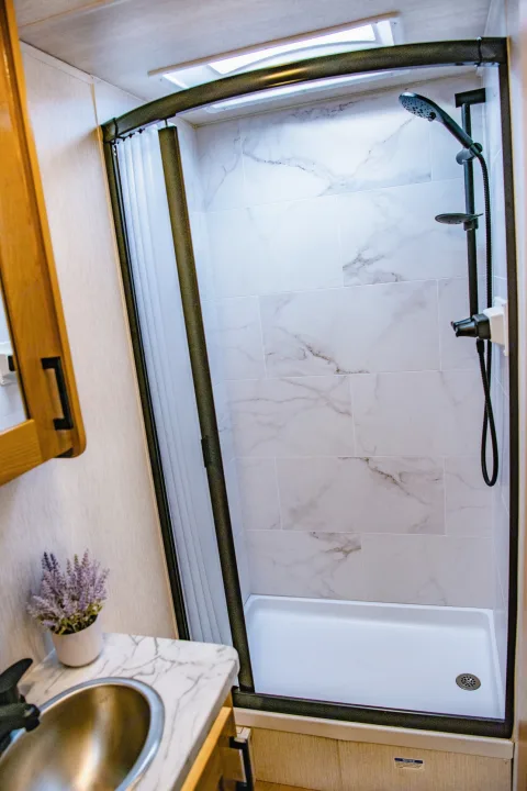 Compact and modern RV rental bathroom showcasing a clean shower, white tiles, and vanity.. Nexus 29T 2026