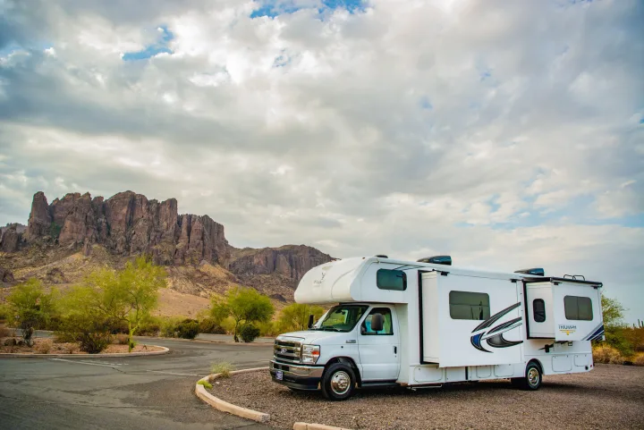 White RV rental parked in a scenic desert landscape with rugged mountains under a cloudy sky.. Nexus Other 2026