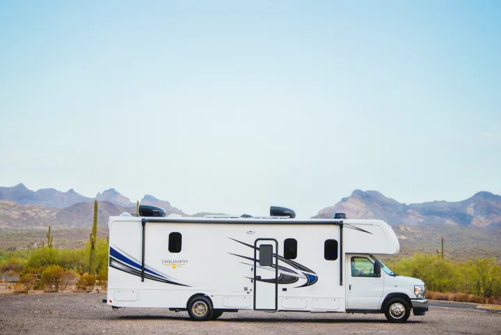 White rv rental parked in a scenic desert with saguaro cacti and distant mountains under a clear sky.. Nexus Other 2026