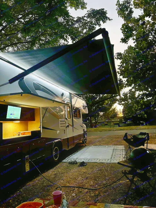 Relaxing evening at an RV rental campsite: lit awning, outdoor TV, grill, and comfortable setup under twilight.. Forest River Forester 2861DS 2016