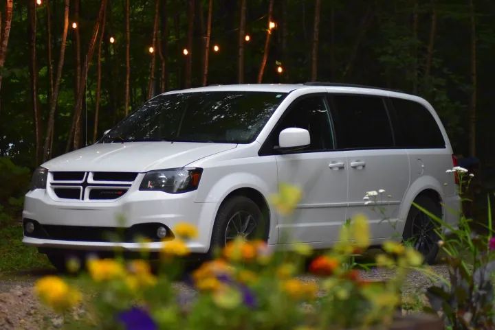 White Dodge minivan parked in a lush, illuminated forest. Great for road trips or as an 'rv rental' alternative for adventurers.. Dodge Dodge Grand Caravan GT 2017 2017