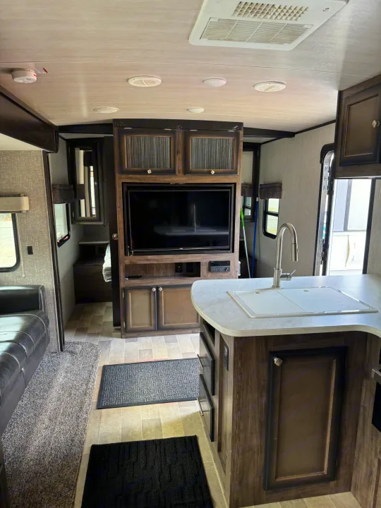 RV rental interior showing a modern kitchen with sink, entertainment center, and sofa in a well-lit space.. Heartland RVs Mallard 2019