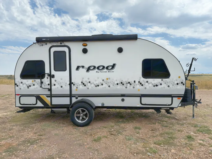 White r-pod travel trailer with honeycomb graphics, a great rv rental option for camping, parked on gravel.. R-Pod R-Pod Trailer 2021