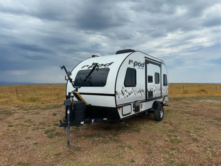 Modern R-Pod travel trailer for RV rental, parked in a dry field under cloudy skies, ready for adventure.. R-Pod R-Pod Trailer 2021