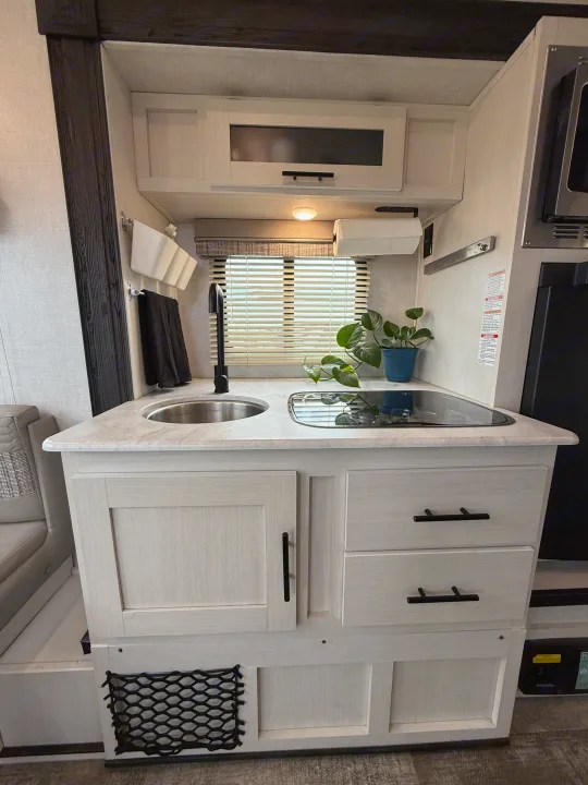 Experience comfort in this RV rental! Bright, modern kitchen with sink, cooktop, light cabinetry, and handy storage solutions.. R-Pod R-Pod Trailer 2021