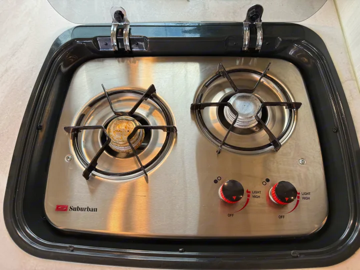 Two-burner Suburban stove, ideal for an RV rental kitchen. Features a stainless steel finish and protective glass lid.. R-Pod R-Pod Trailer 2021