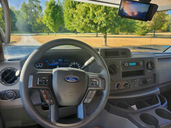 View from inside a Ford RV rental, showing the steering wheel, digital dashboard, and rearview camera screen.. Forester LE 2023