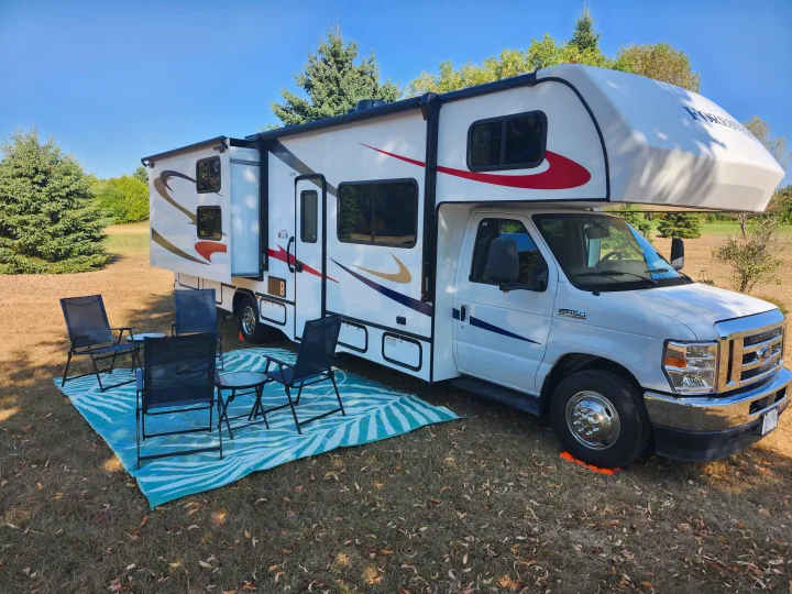 White rv rental ready for camping! Features an extended slide-out, outdoor chairs, and rug for leisure.. Forester LE 2023