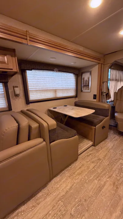 Spacious RV rental interior featuring a cozy dining dinette, plush seating, and ample overhead lighting. Perfect for travel.. Thor Hurricane 2019