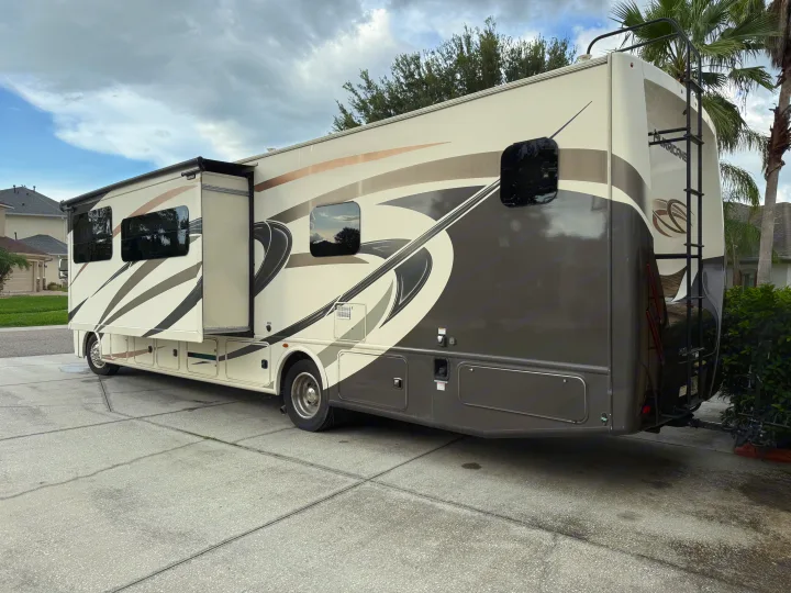 Spacious Class A RV motorhome parked on a driveway, with extended slide-out. Perfect for your next rv rental journey.. Thor Hurricane 2019