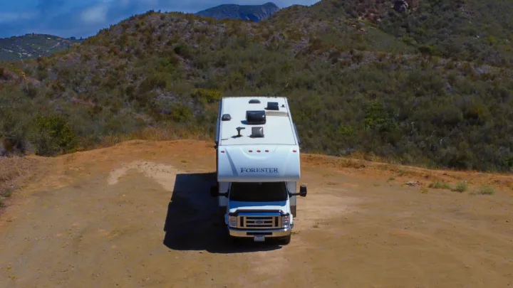 Experience nature with this RV rental! A white Forester motorhome is parked on a dirt path with rugged hills in the background.. Forest River Forester 3171DS 2016