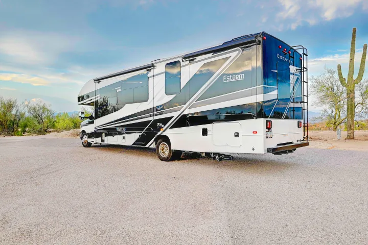 Discover adventure! Rent this sleek black & white Entegra Esteem RV, parked in a scenic desert landscape with a towering saguaro.. Entegra Esteem 2025