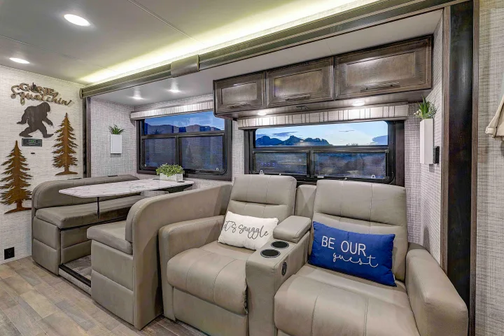 Spacious RV rental interior featuring comfortable recliners, a dining booth, and scenic windows. Perfect for your next adventure!. Entegra Esteem 2025