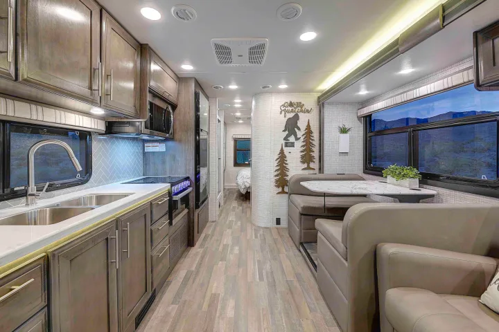 Spacious, modern rv rental interior: a full kitchen, cozy dinette, and bright hallway leading to the bedroom.. Entegra Esteem 2025