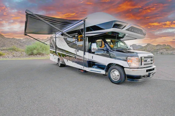 Black & white Entegra RV rental parked in a striking desert scene at sunset with an extended awning.. Entegra Esteem 2025