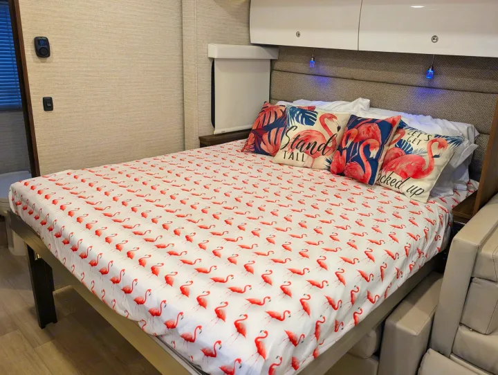 Bright flamingo bed in an RV rental, featuring custom bedding & throw pillows, creating a fun and cozy interior.. Winnebago View 2025