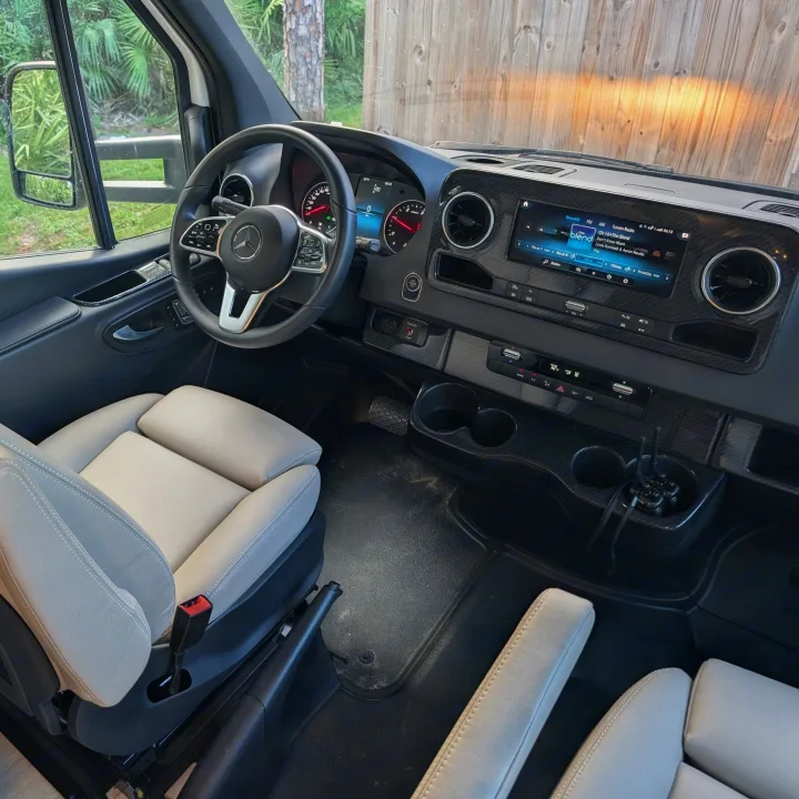 Spacious RV rental van interior, featuring a modern dashboard, infotainment screen, comfortable seating, and radio.. Winnebago View 2025