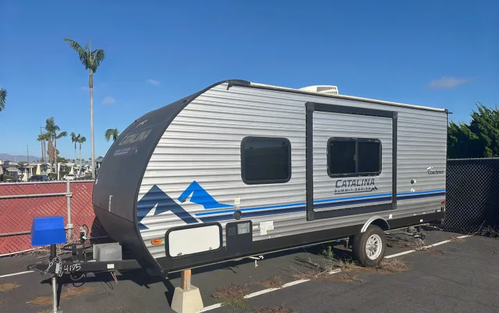 Silver Catalina Summit Series travel trailer, an ideal RV rental, parked outdoors on a sunny day. Palm trees visible.. Coachmen Catalina Summit Series 7 2022