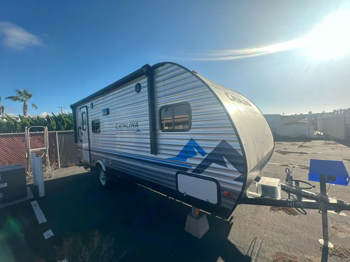 This sleek Catalina travel trailer, perfect for your next RV rental adventure, gleams under the bright sun, showcasing its mountain graphics.. Coachmen Catalina Summit Series 7 2022