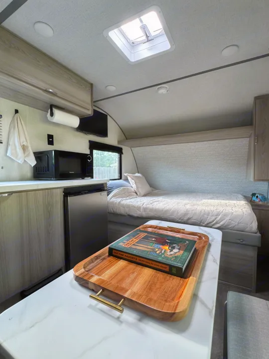 Cozy RV rental interior: compact kitchen, bed, and skylight create a comfortable home on wheels for your next adventure.. Forest River Wildwood FSX Platinum 2025