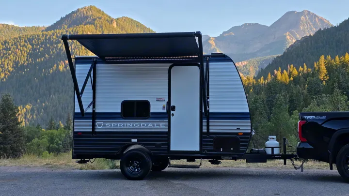 This Springdale travel trailer rv rental, hitched to a pickup truck, is parked amidst majestic mountains, ready for outdoor adventures.. Keystone Springdale 2026