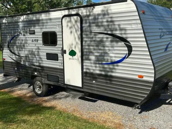 Gray Z-Series Lite travel trailer, an RV rental with black and blue decals, parked on gravel for your next adventure.. Crossroads RV Z-1 Lite 2017