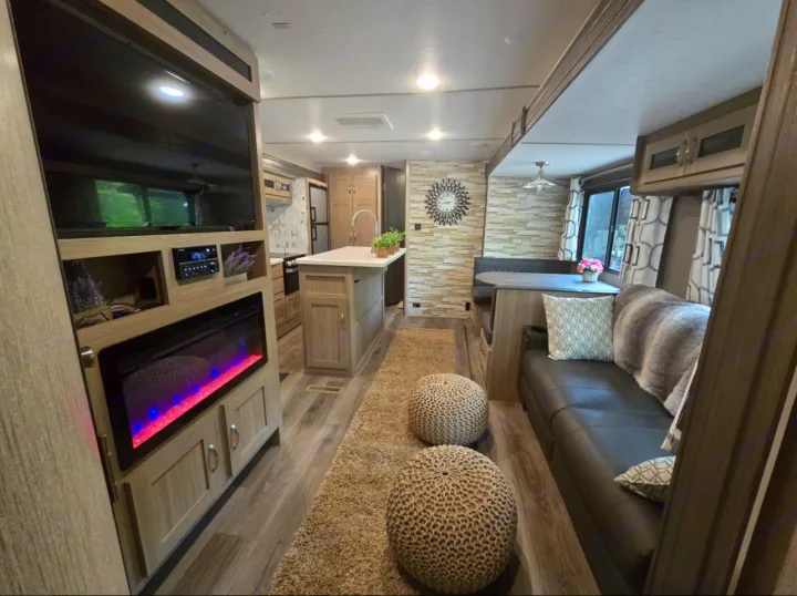 This modern RV rental features a full kitchen island, TV & fireplace in the living area, and a comfy dining booth.. Coachmen Forest River Freedom Express Liberty Series M-320 BHDS 2021