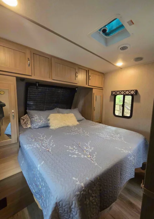 Spacious RV rental bedroom features a comfy queen bed, ample storage, and natural light. Perfect for travel.. Coachmen Forest River Freedom Express Liberty Series M-320 BHDS 2021