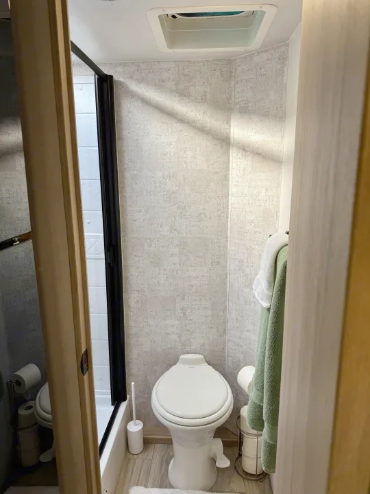 Compact RV rental bathroom with a Dometic toilet, shower, and ceiling vent.. Winnebago Micro Minnie 2025