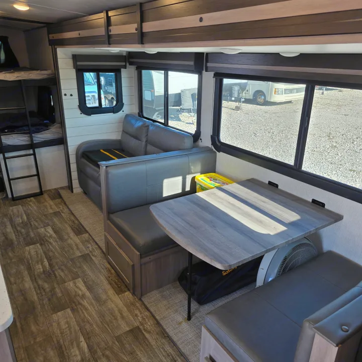 RV rental interior: a bright living area with a dining booth, bunk beds, and large windows offering outdoor views.. Crossroads RV Sunset Trail Super Lite 2022