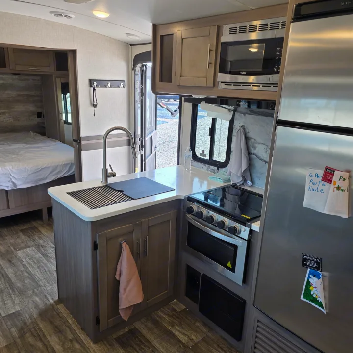 Spacious RV rental interior featuring a modern kitchen with stainless steel appliances and a comfortable bedroom.. Crossroads RV Sunset Trail Super Lite 2022