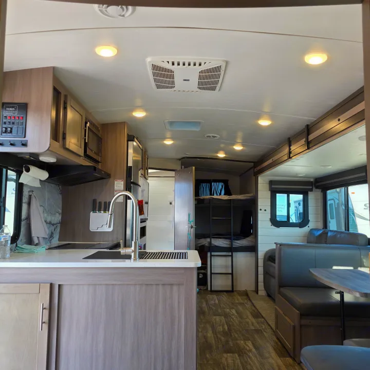 Spacious, modern RV rental interior: kitchen, dining area, and bunk beds. Perfect for family adventures.. Crossroads RV Sunset Trail Super Lite 2022