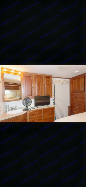 This RV rental offers a well-appointed bedroom with a vanity sink, mirror, wooden cabinets, dresser, and TV for a comfortable stay.. Itasca Horizon 2002
