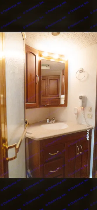 RV rental's compact bathroom: functional sink and vanity, lighted mirror, wall-mounted hairdryer, with shower to the left.. Itasca Horizon 2002