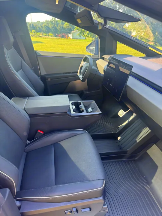 Modern Cybertruck cabin: driver's seat, yoke wheel, large screen, durable mats. Ideal for adventure or rv rental trips.. Tesla Cybertruck 2025