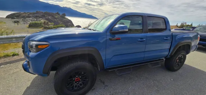 Blue Toyota Tacoma TRD Pro truck parked by a scenic lake. Perfect for adventures often taken with an RV rental.. toyota Tacoma 2018