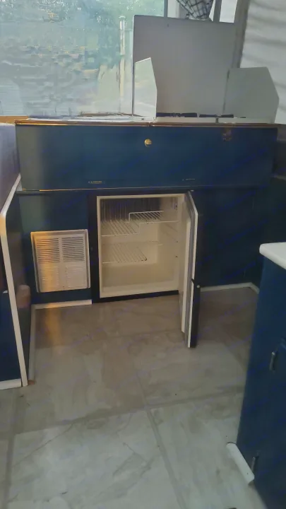 Inside this RV rental: A compact kitchen area featuring a top-mounted stove, open mini-fridge, and vent unit.. Coleman Destiny Santa Fe 1996